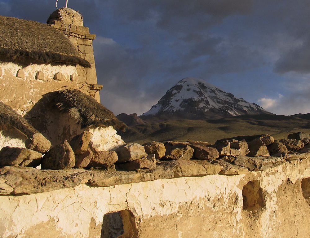 Bâtisse en adobe du village de Tomarapi devant la silhouette enneigée du Nevado Sajama, Bolivie